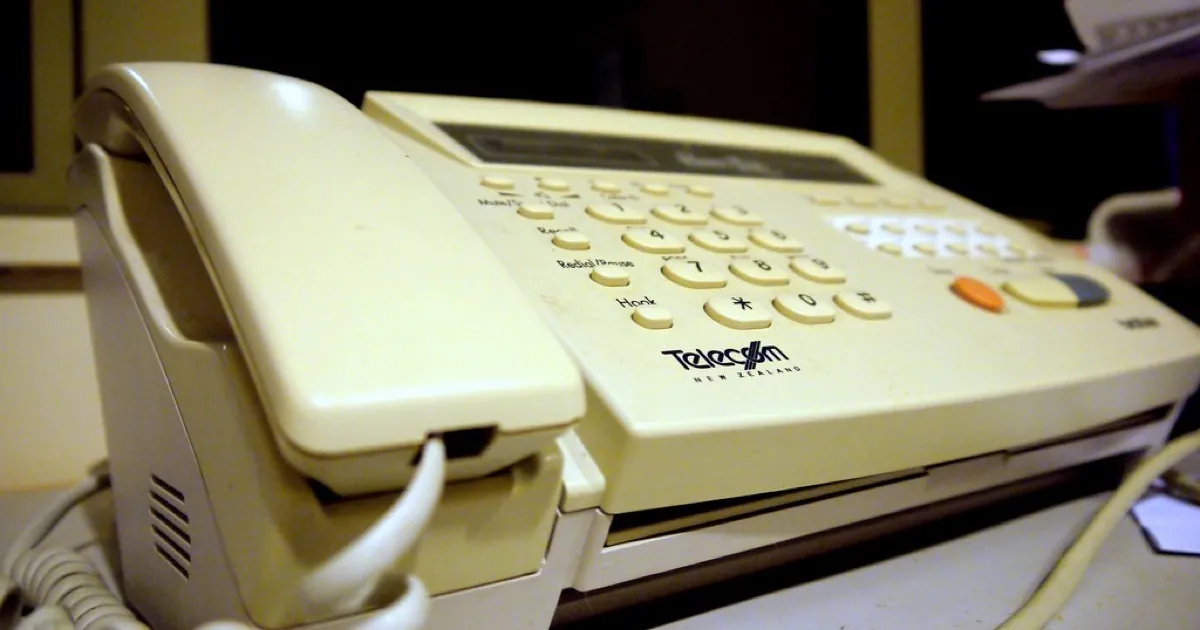 A vintage fax machine on a wooden counter